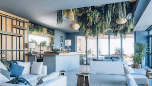 A modern living room with a sofa, coffee table, and hanging plants.