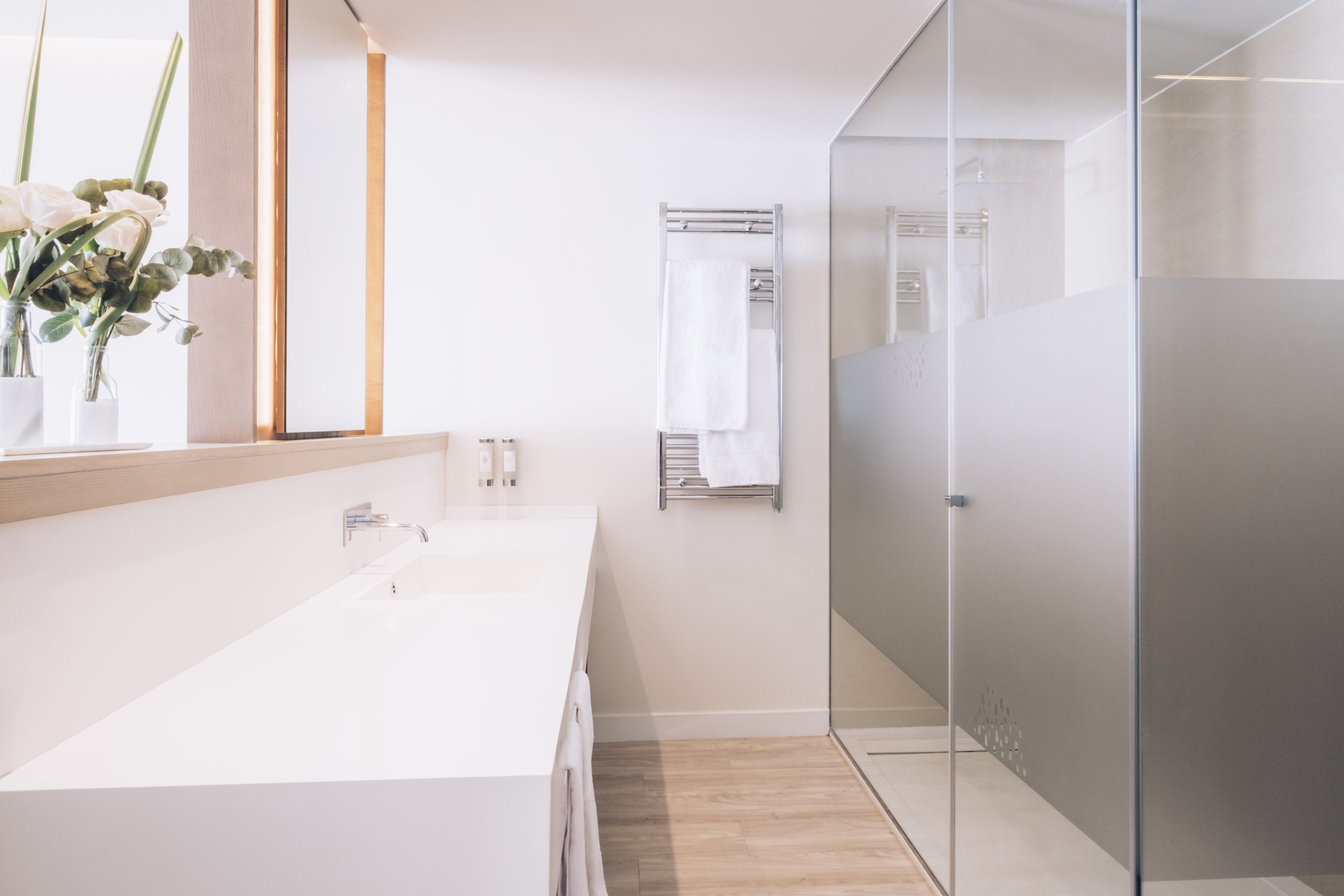 Une salle de bain moderne avec un grand lavabo blanc, une douche en verre et un porte-serviettes.