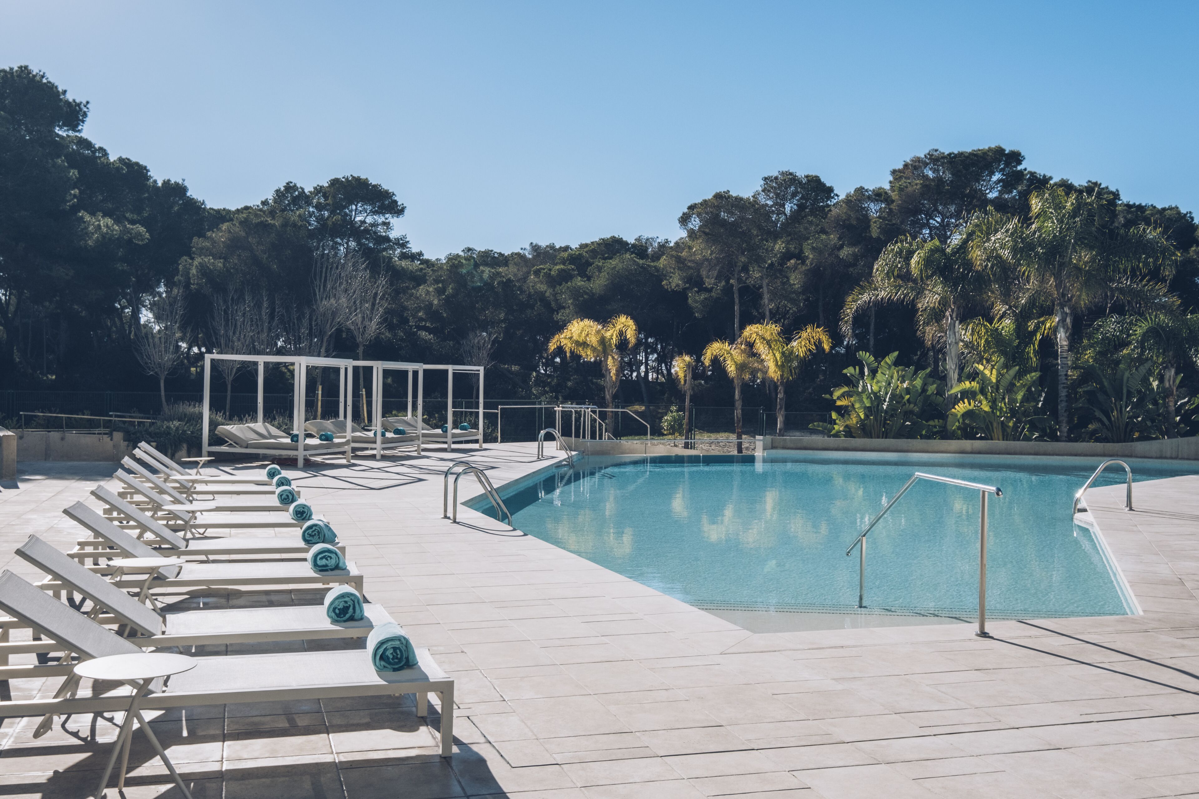 Una piscina con sillas de descanso y un área de estar cubierta.