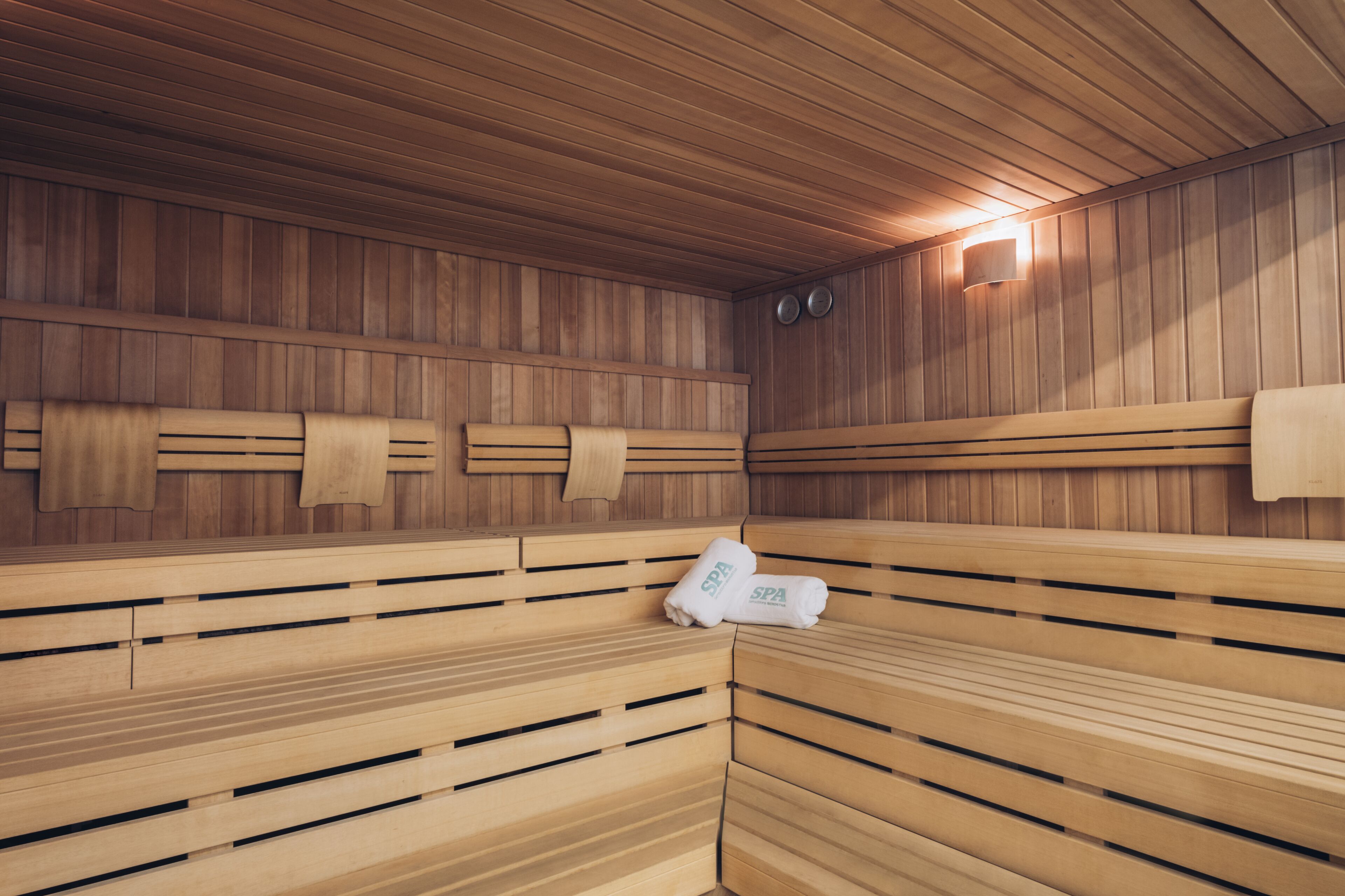 A sauna with wooden benches and a towel rack.