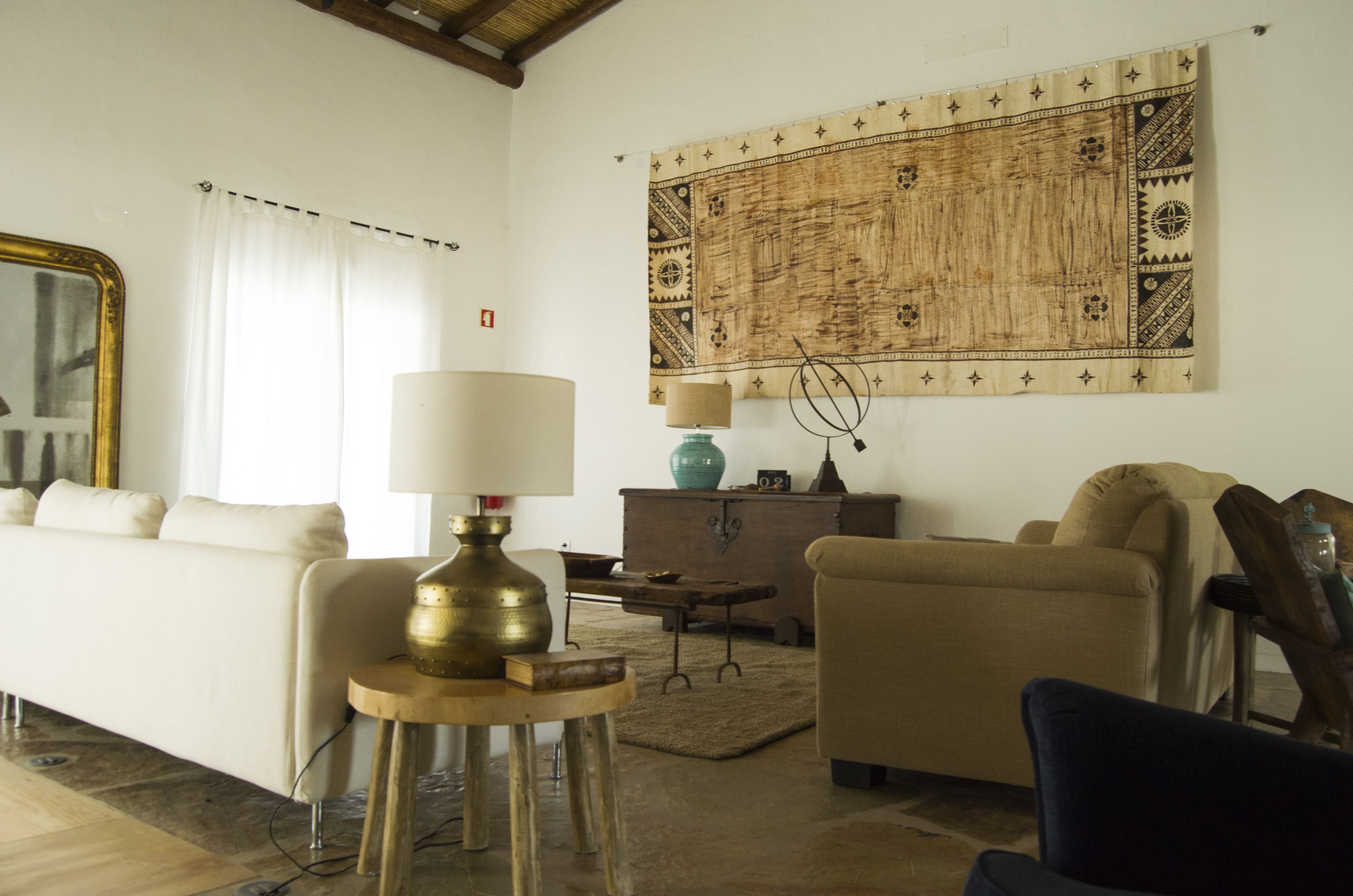 A living room with a sofa, a lamp, a coffee table, and a tapestry on the wall.