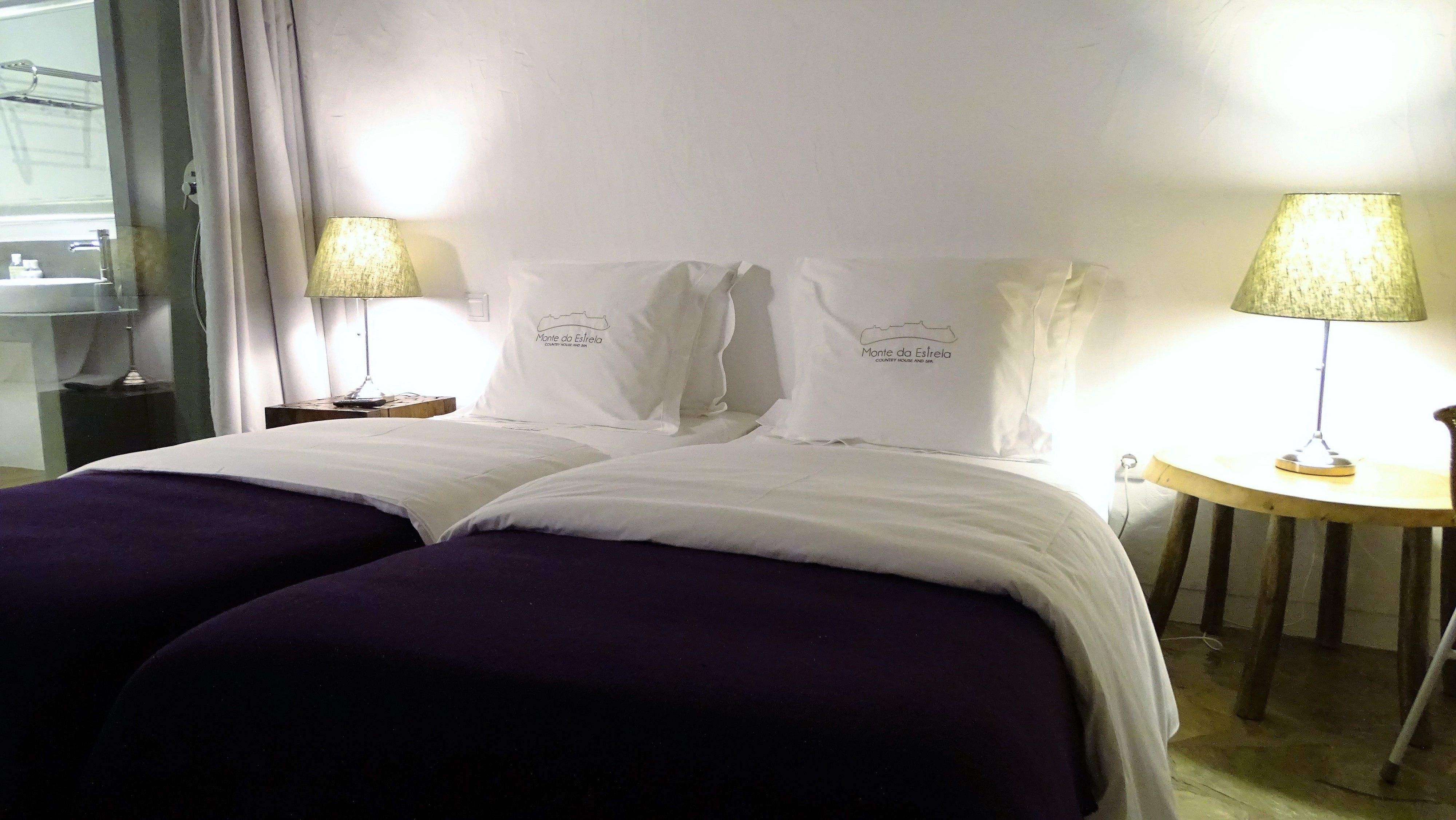A hotel room with a bed, two bedside tables, and lamps.