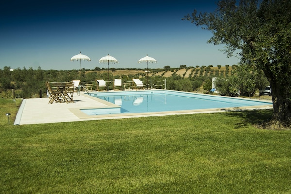 Una piscina al aire libre de temporada, sombrillas
