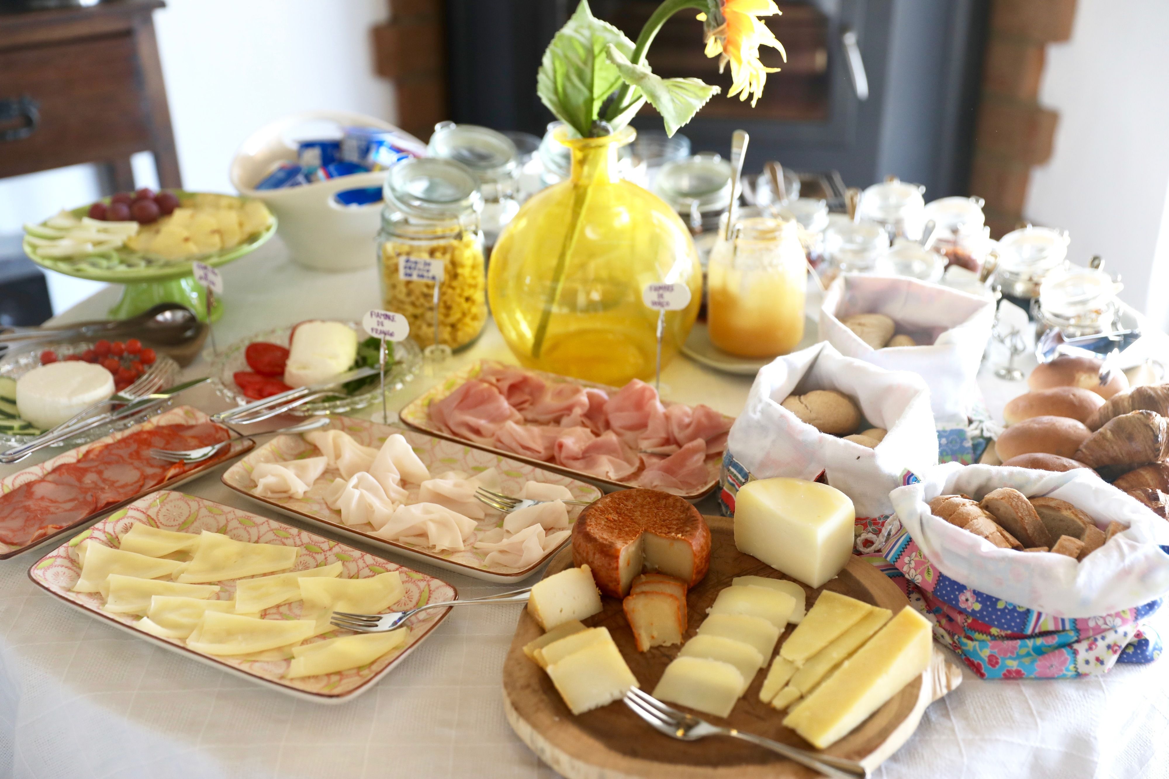A buffet table with various food items including cheeses, meats, and pastries.
