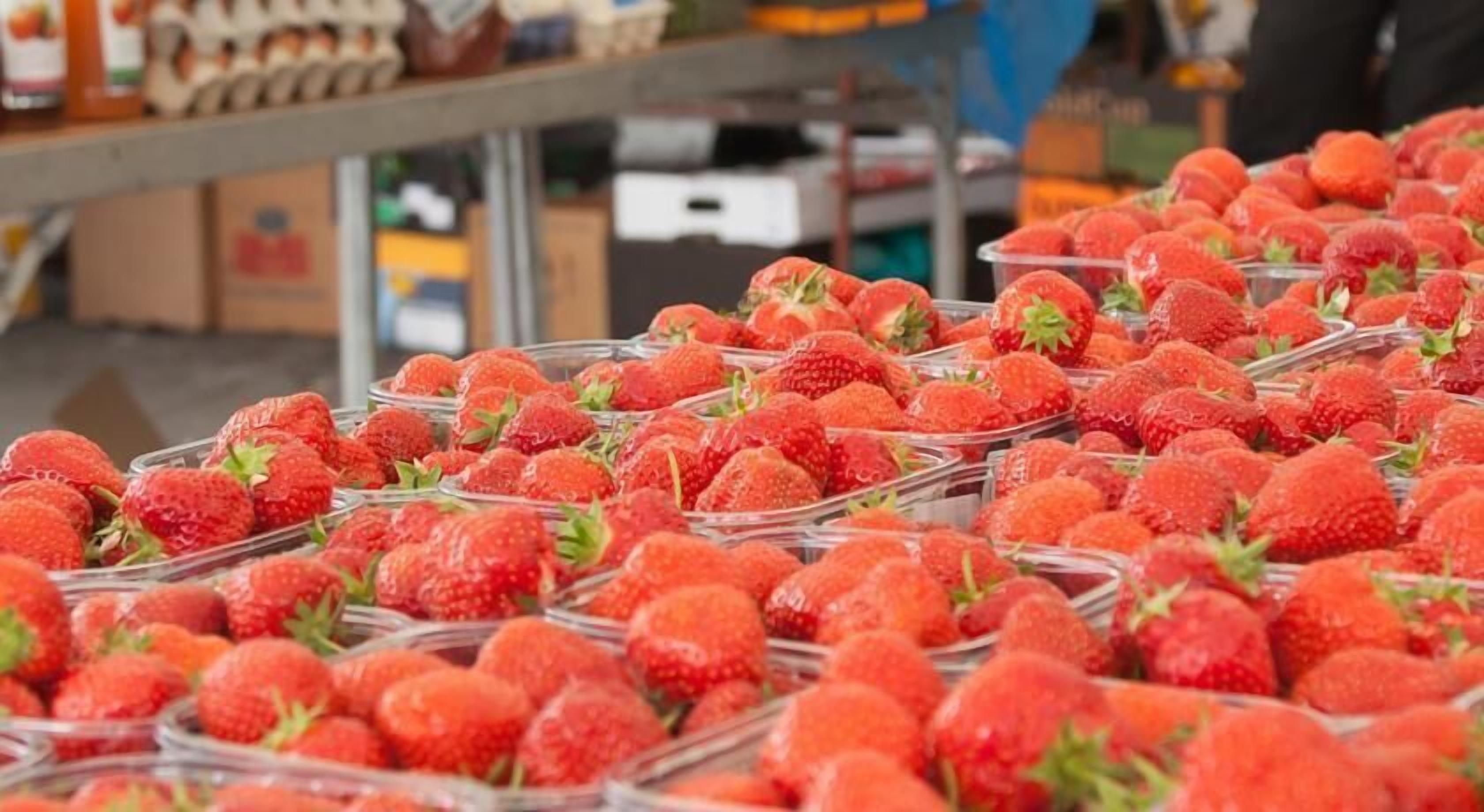 A display of strawberries in clear containers at a market.