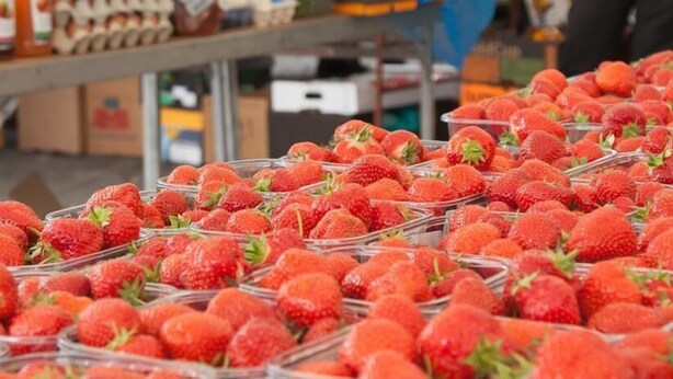 Aardbeien in glazen bakken op een markt.