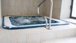 A hot tub with a metal ladder, surrounded by tiled flooring. - Hotel Teratermal (Valdeavellano de Tera)