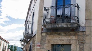 A building with a stone facade, a balcony with metal railings, and a door with a decorative design. - Hotel Teratermal (Valdeavellano de Tera)