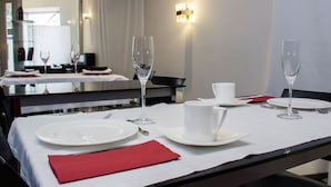 A hotel dining table set with white plates, silverware, and clear wine glasses, with a red napkin and a white cup. - Hotel Teratermal (Valdeavellano de Tera)