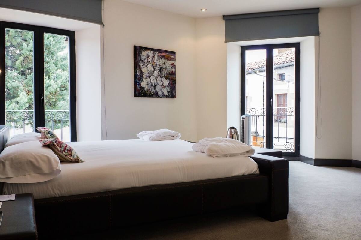 Un dormitorio con una cama grande, un cuadro en la pared y un balcón con vistas.
