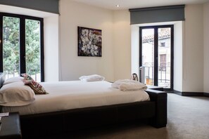 Een slaapkamer met een groot bed, een schilderij aan de muur en een balkon met uitzicht.
