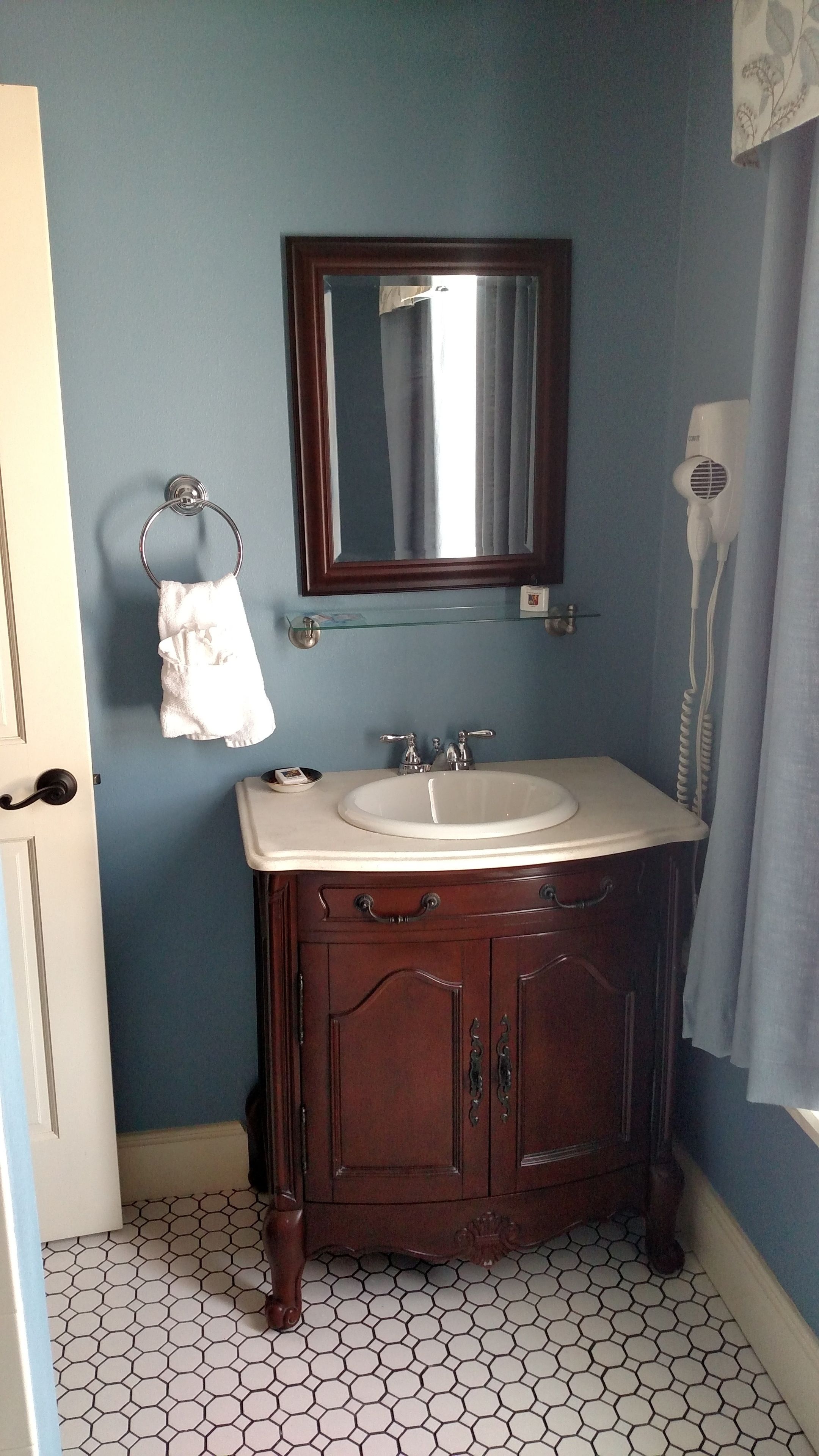 A bathroom with a sink, mirror, towel rack, and hairdryer.
