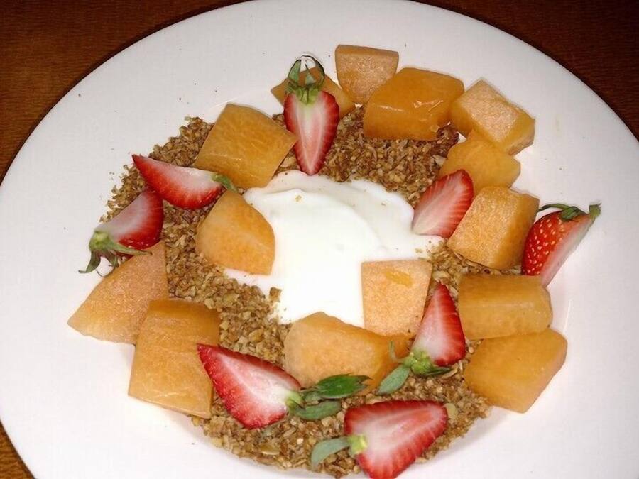 A plate of granola with fruit and yogurt.