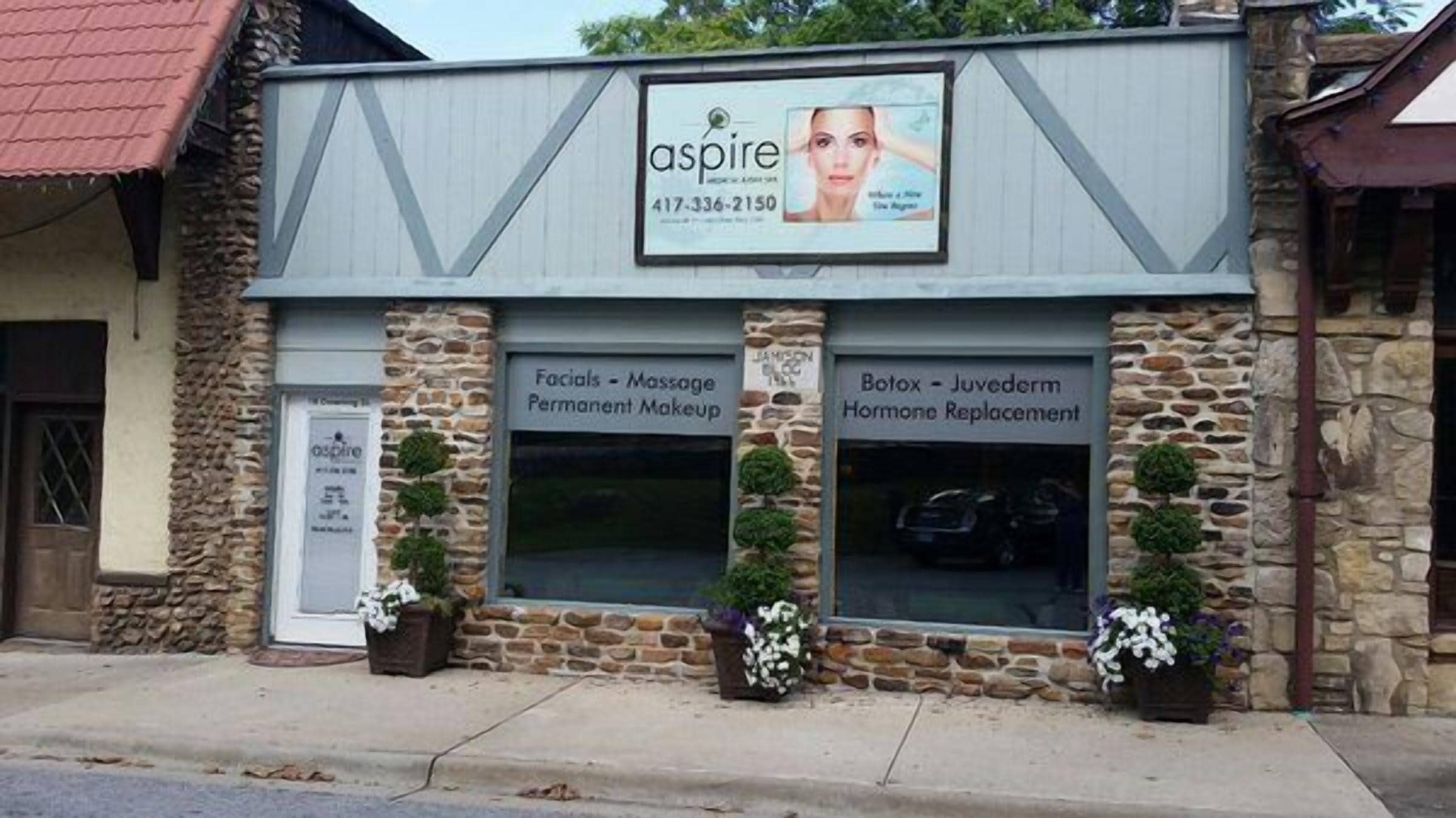 A building with a sign for 'aspire' offering services like facials, massage, permanent makeup, Botox, and hormone replacement.
