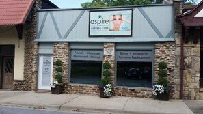 A building with a sign for 'aspire' offering services like facials, massage, permanent makeup, Botox, and hormone replacement. - Ye Old English Inn (Hollister)