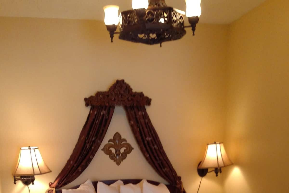 Een groot bed met hemel, twee bedlampen en een kroonluchter.