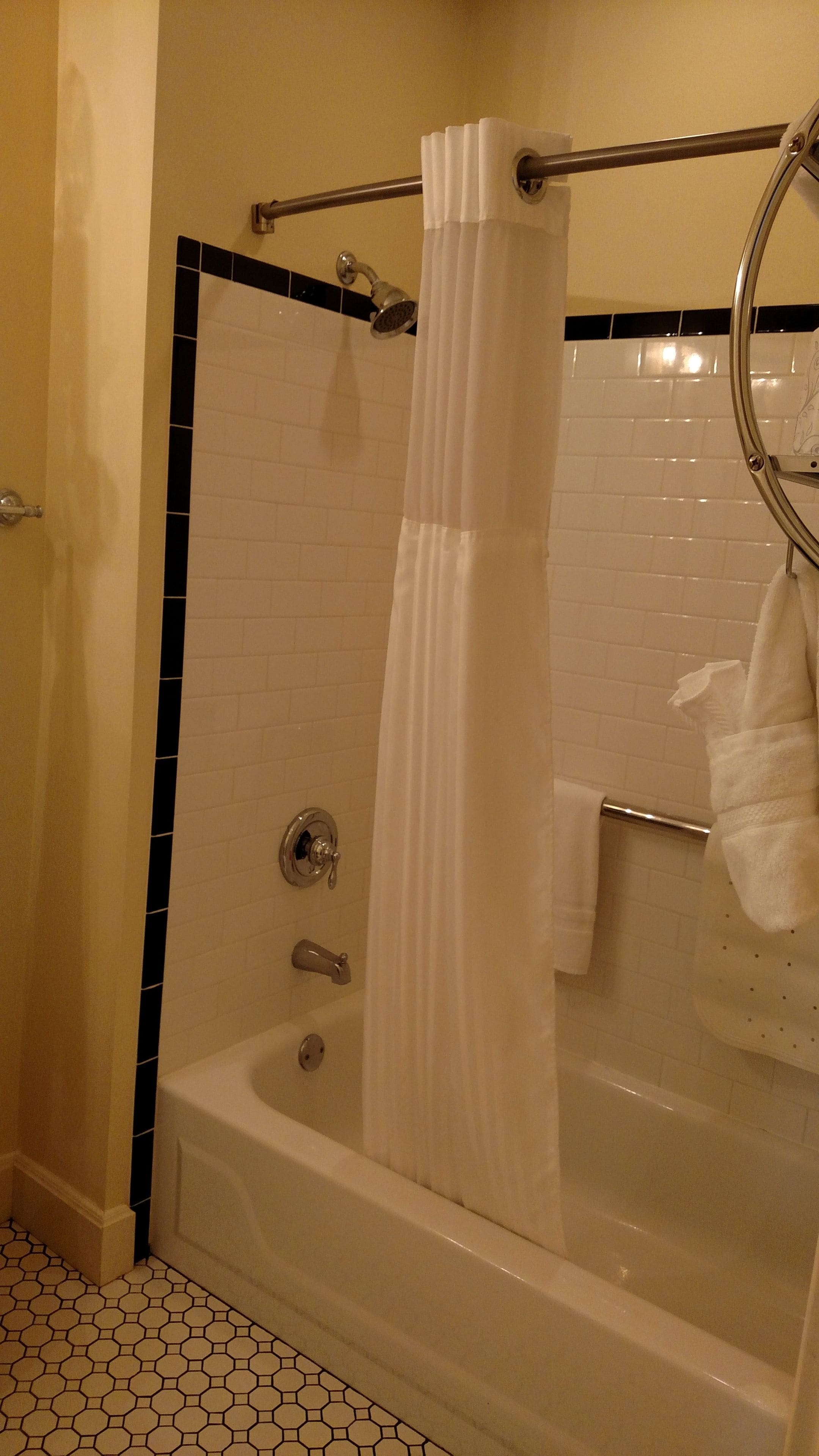 A bathroom with a bathtub, a shower curtain, and a towel rack.