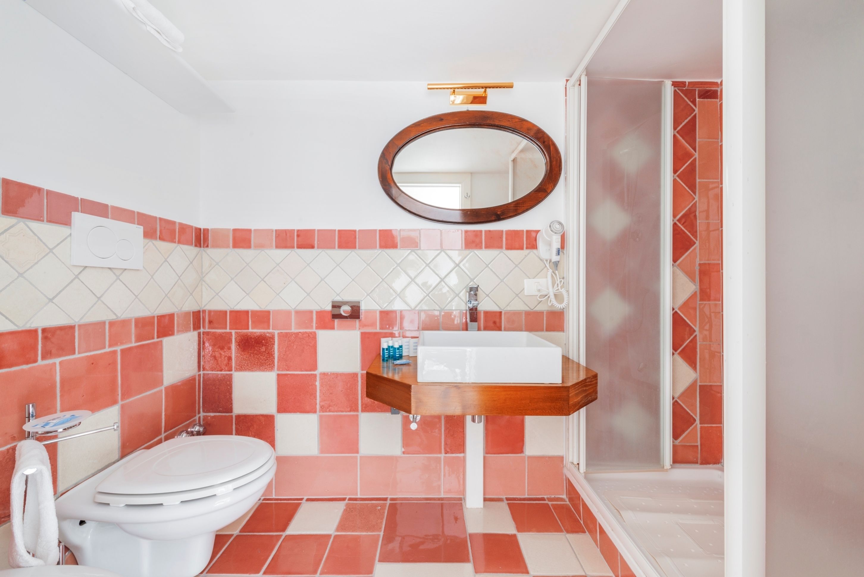 A bathroom with a white toilet, a wooden vanity with a white sink, and a mirror above the sink.
