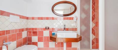 A bathroom with a white toilet, a wooden vanity with a white sink, and a mirror above the sink.