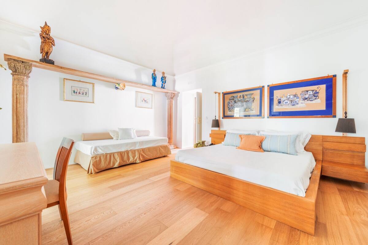 A bedroom with two beds, wooden furniture, and framed artwork on the walls.
