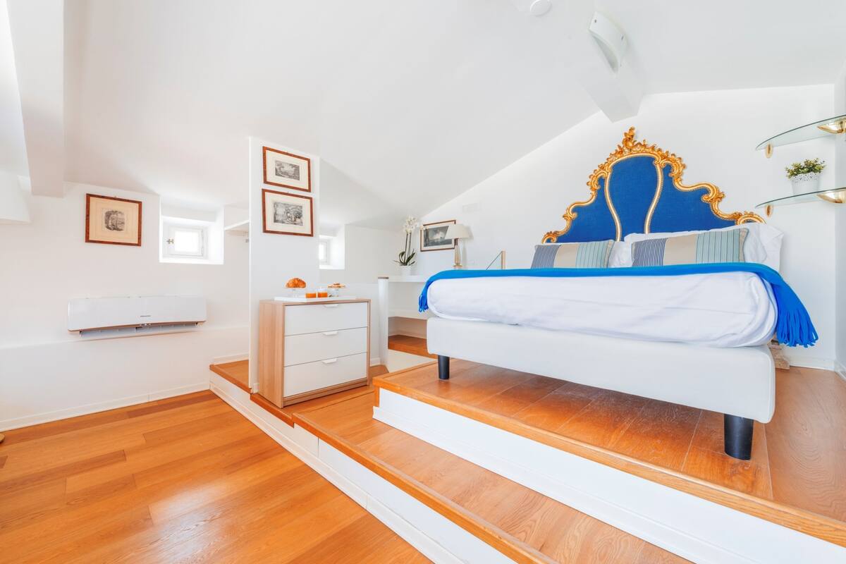A bedroom with a bed, white dresser, and a small table with a lamp.