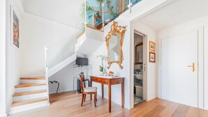 A spacious living area with a wooden staircase, a dining table with chairs, and a large mirror on the wall. - Palazzo Sassi (Meta)