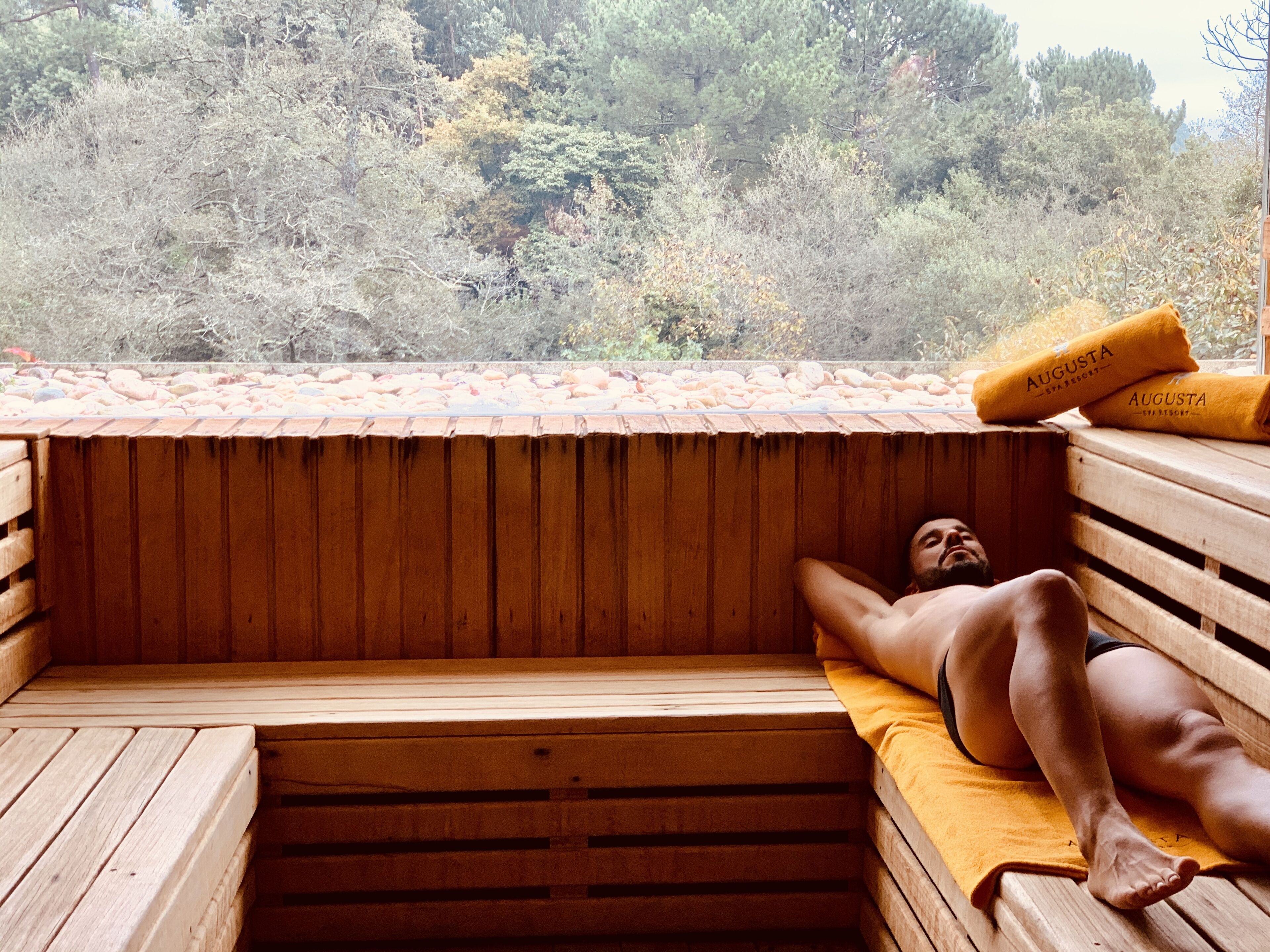 Una sauna con un banco de madera y otro banco con una toalla.