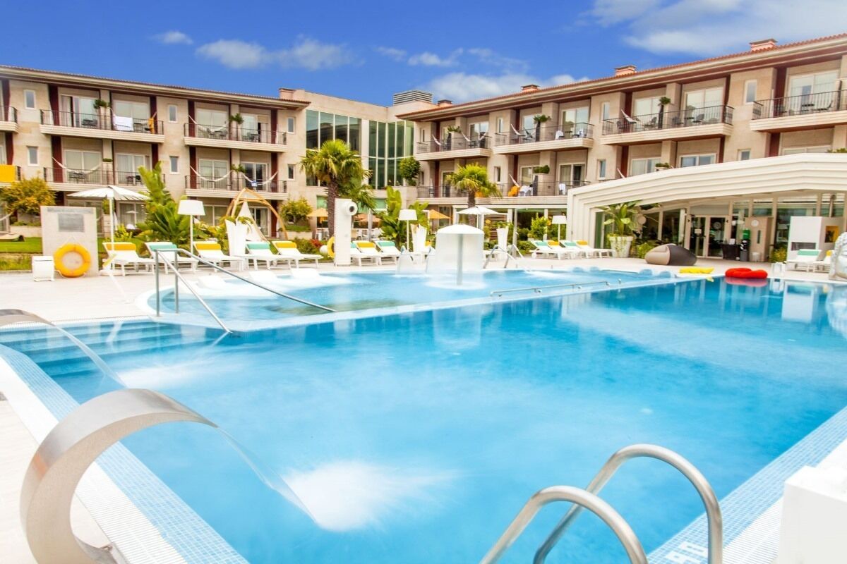 Un hotel con una piscina grande, varios balcones y tumbonas.