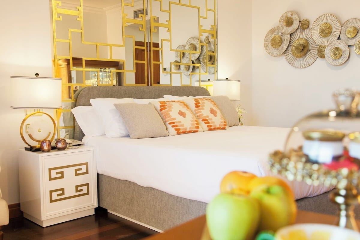 Quarto bem arrumado com cama, mesas de cabeceira e arte decorativa na parede.