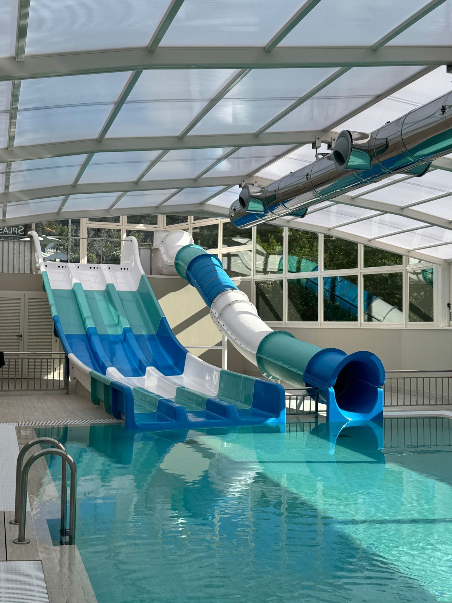 Una piscina con un tobogán de colores y otro tobogán acuático.
