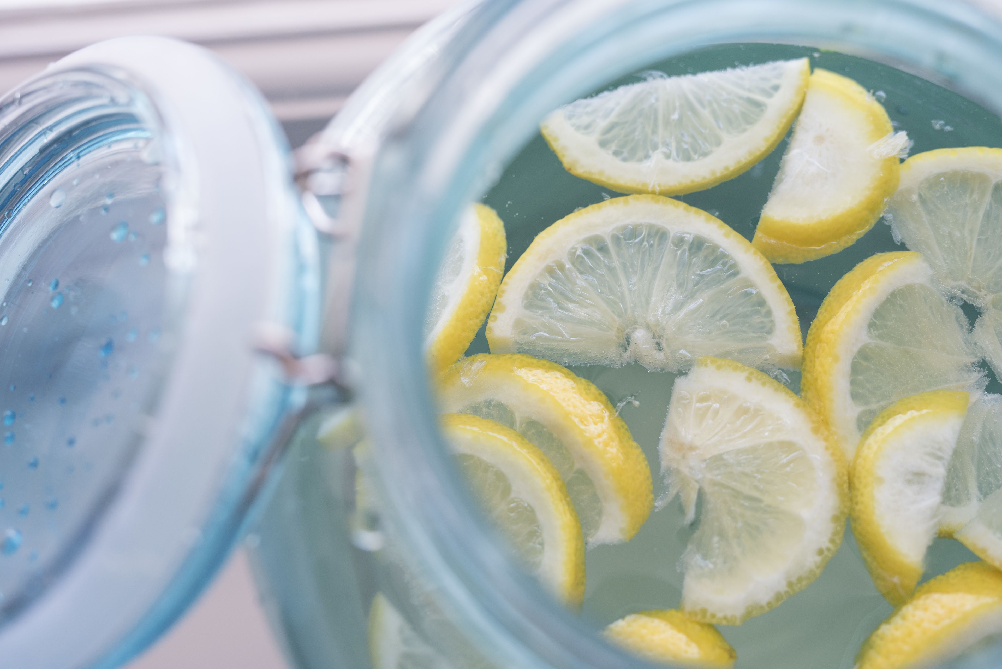 A glass container with a clear liquid and lemon slices.
