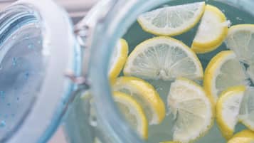 A glass container with a clear liquid and lemon slices.