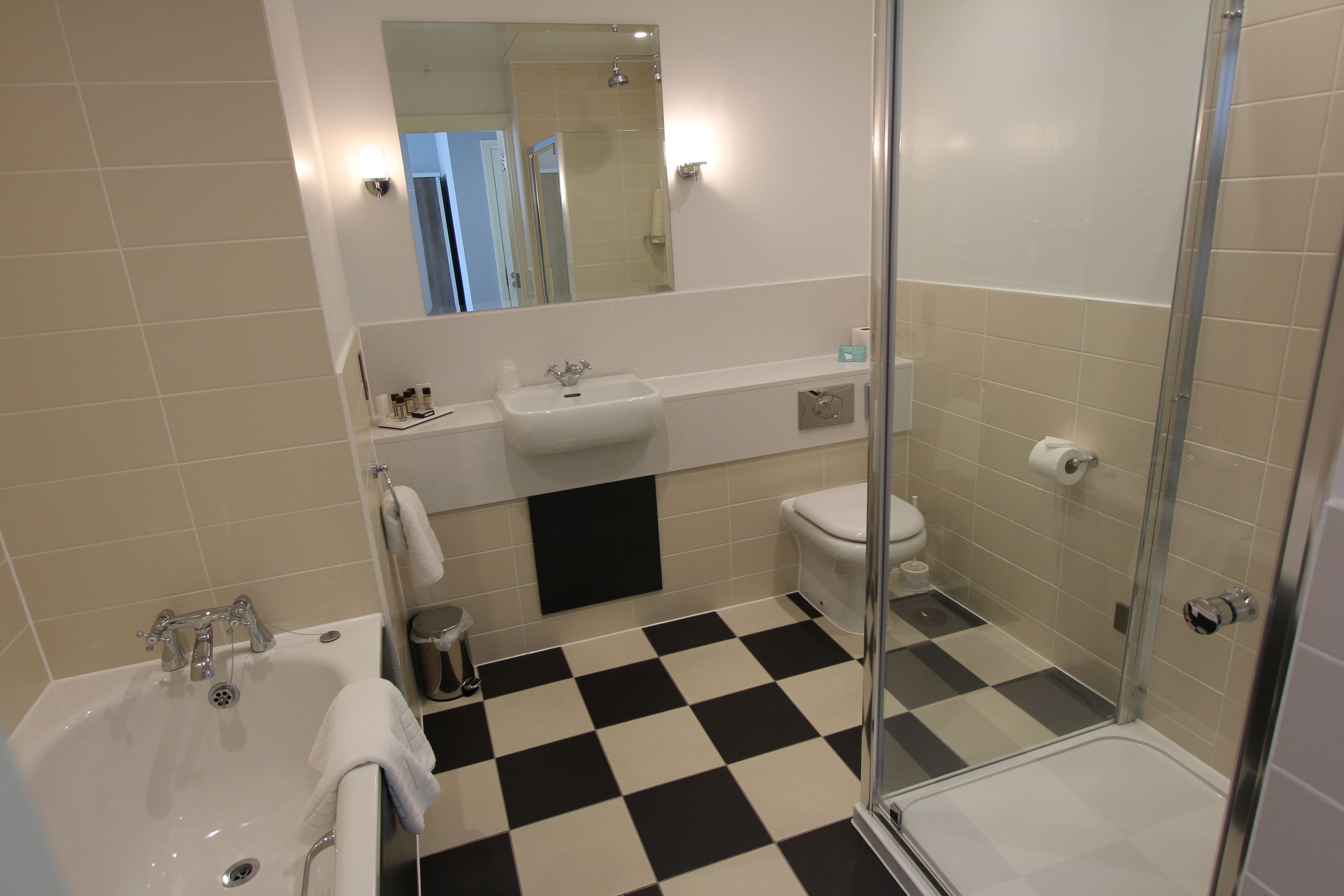 A bathroom with a checkered floor, a sink, a toilet, and a shower.