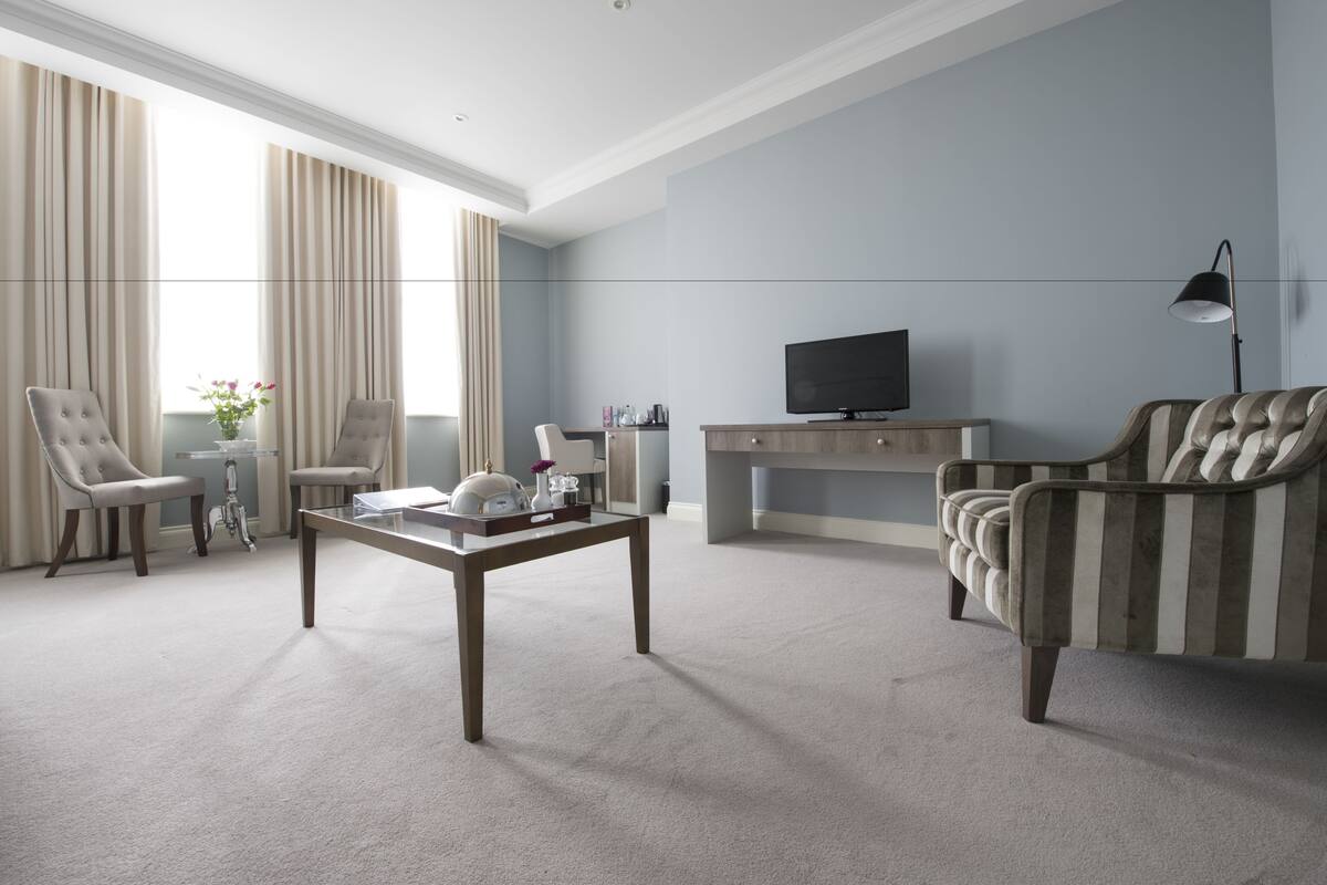 A modern living room with a sofa, chairs, a coffee table, a TV, and a lamp.