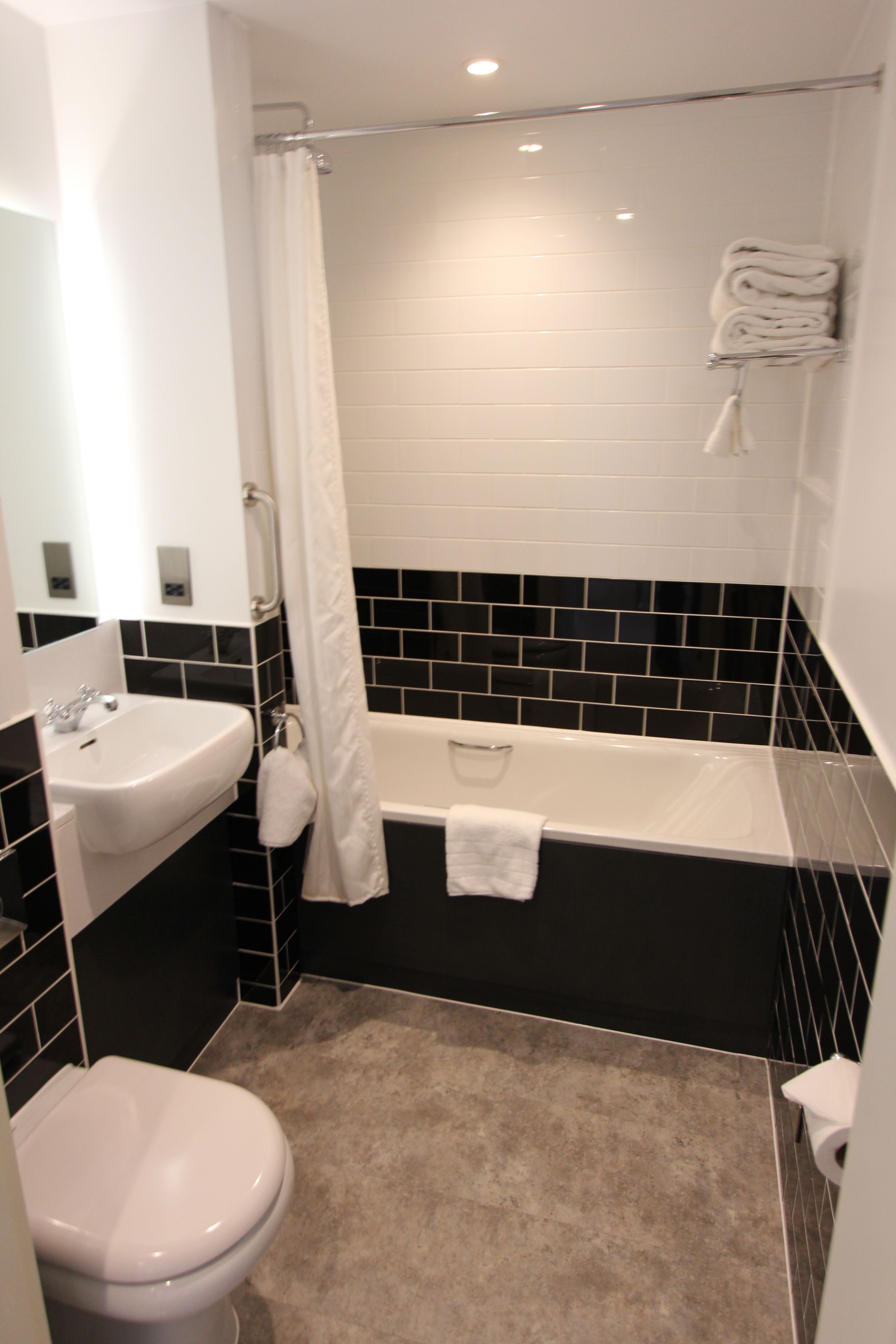 Een badkamer met een witte wastafel, toilet, bad en douchegordijn.