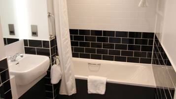 Een badkamer met een witte wastafel, toilet, bad en douchegordijn.