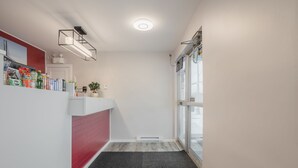 Un couloir étroit avec un mur rouge, un comptoir blanc et un tapis noir.