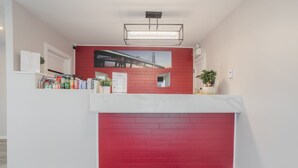 Un espace d’accueil avec un mur en briques rouges, un comptoir d’accueil blanc et une grande fenêtre donnant sur un pont.