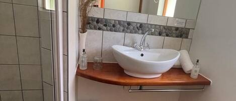Ein Badezimmer mit einem weißen Waschbecken, einem Spiegel, einer kleinen Mülltonne und einer gelben Badmatte.