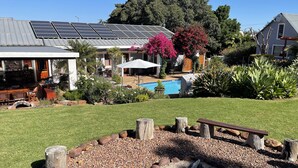 Una propiedad residencial con piscina, paneles solares y un jardín bien cuidado.