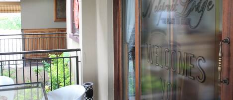 Entrada de un hotel con puerta de vidrio que muestra el letrero "Welcomes You" y "Nelsmit Lodge".