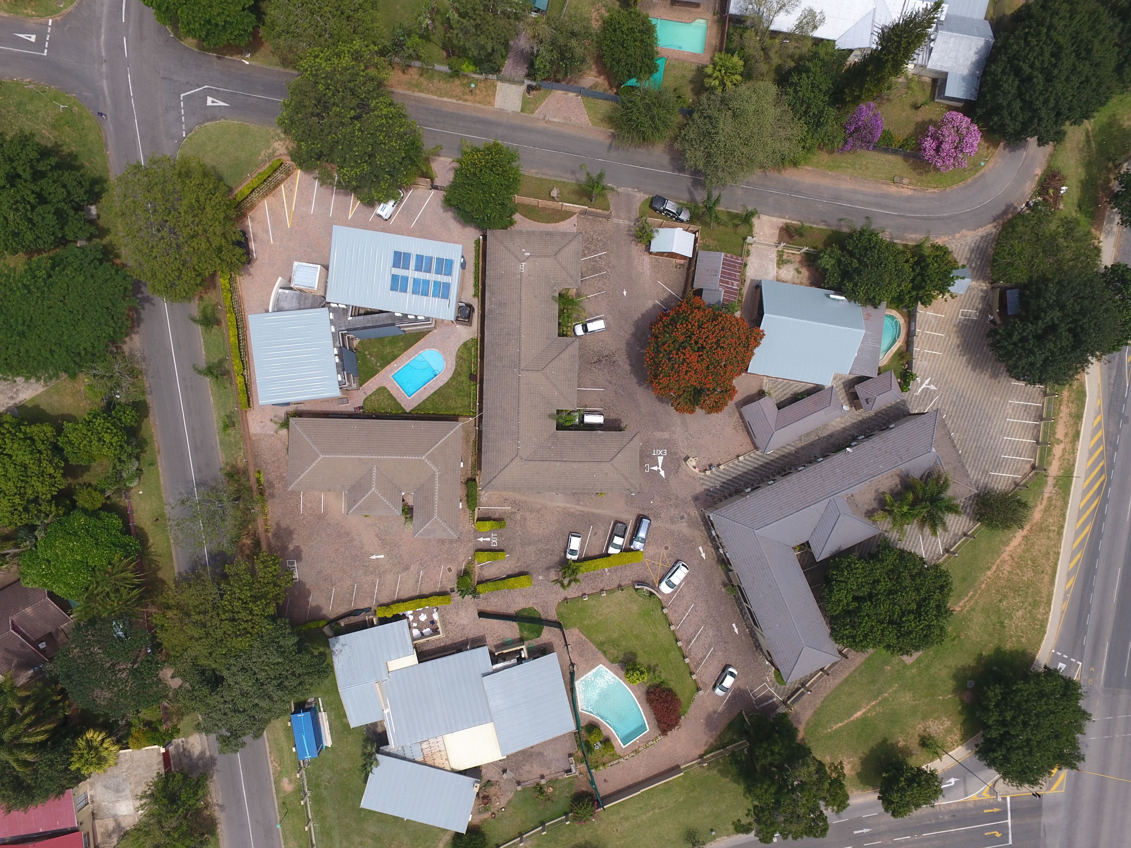 Vista aérea de una zona residencial con varias casas, una piscina y una calle.