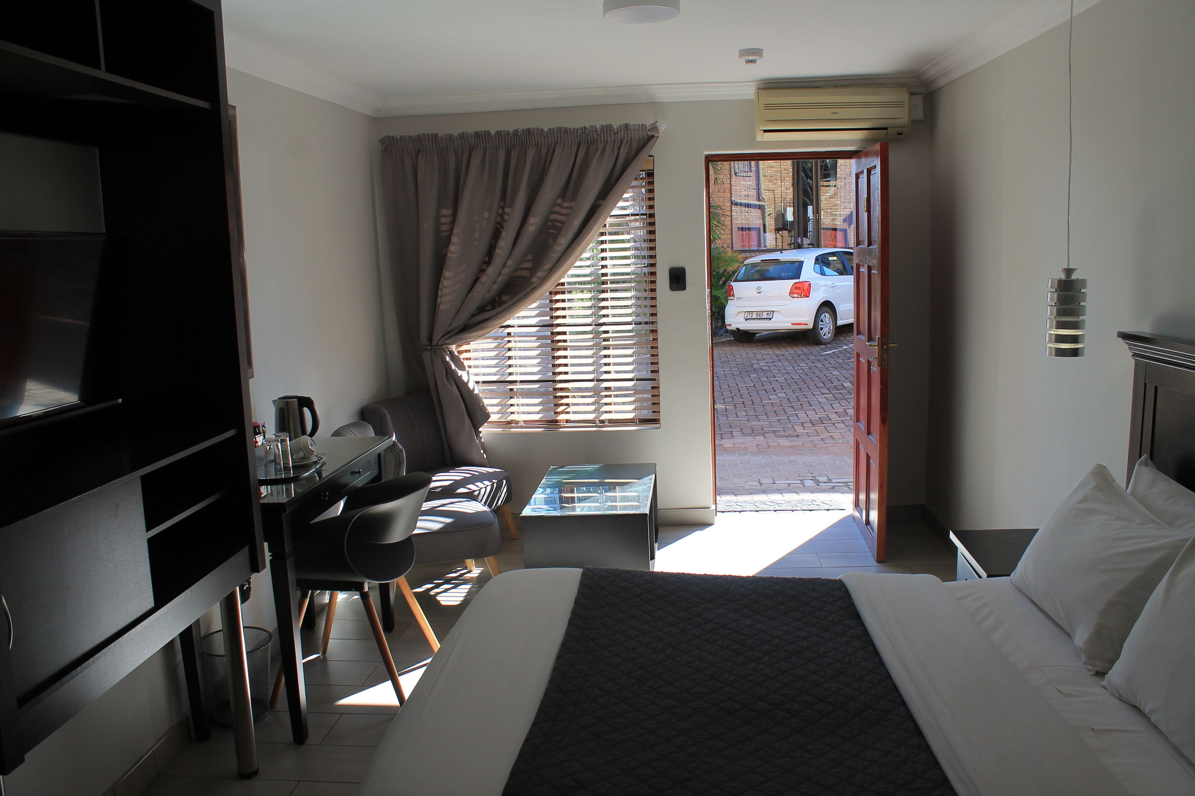 Una habitación de hotel con cama, escritorio, silla y ventana con persianas.
