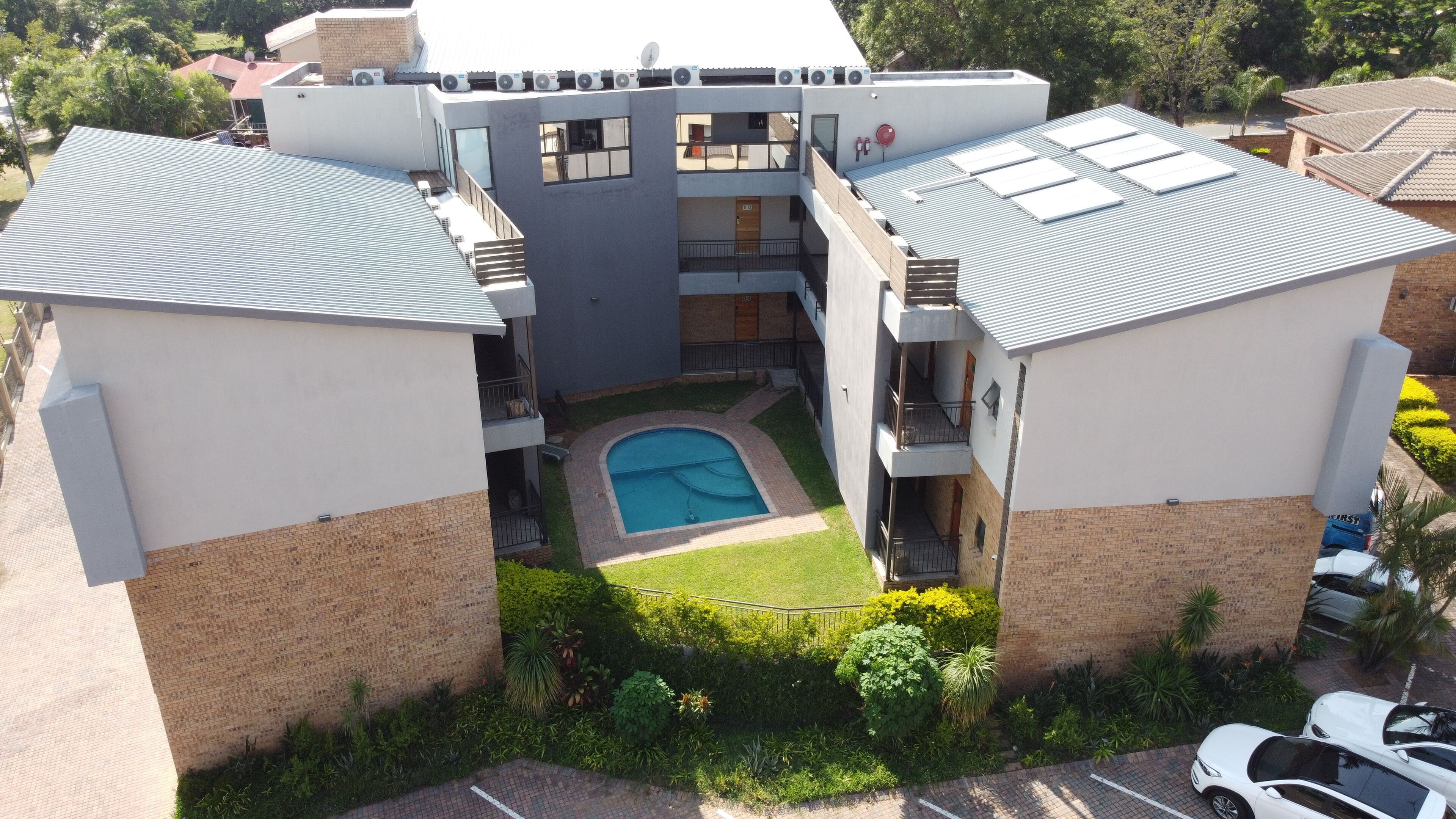 A modern building with a central courtyard, multiple balconies, and a swimming pool.