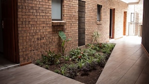 Een modern gebouw met een bakstenen gevel, een kleine tuin met verschillende planten, en een houten vloer.