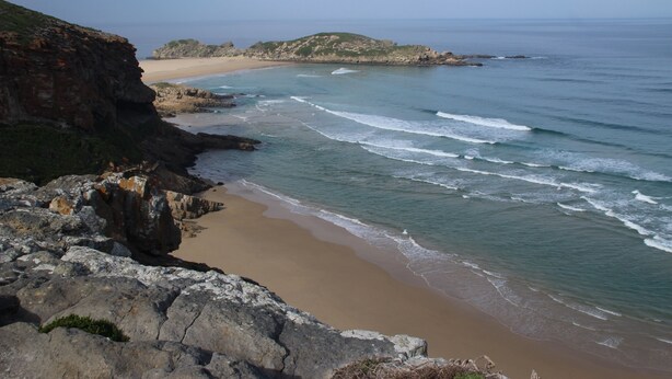 A coastal landscape with a rocky cliff, beach, and ocean. - Anchorage Guest House (Plettenberg Bay)