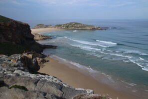 A coastal landscape with a rocky cliff, beach, and ocean. - Anchorage Guest House (Plettenberg Bay)
