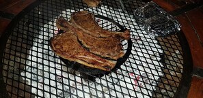 A grill with several steaks cooking. - Anchorage Guest House (Plettenberg Bay)