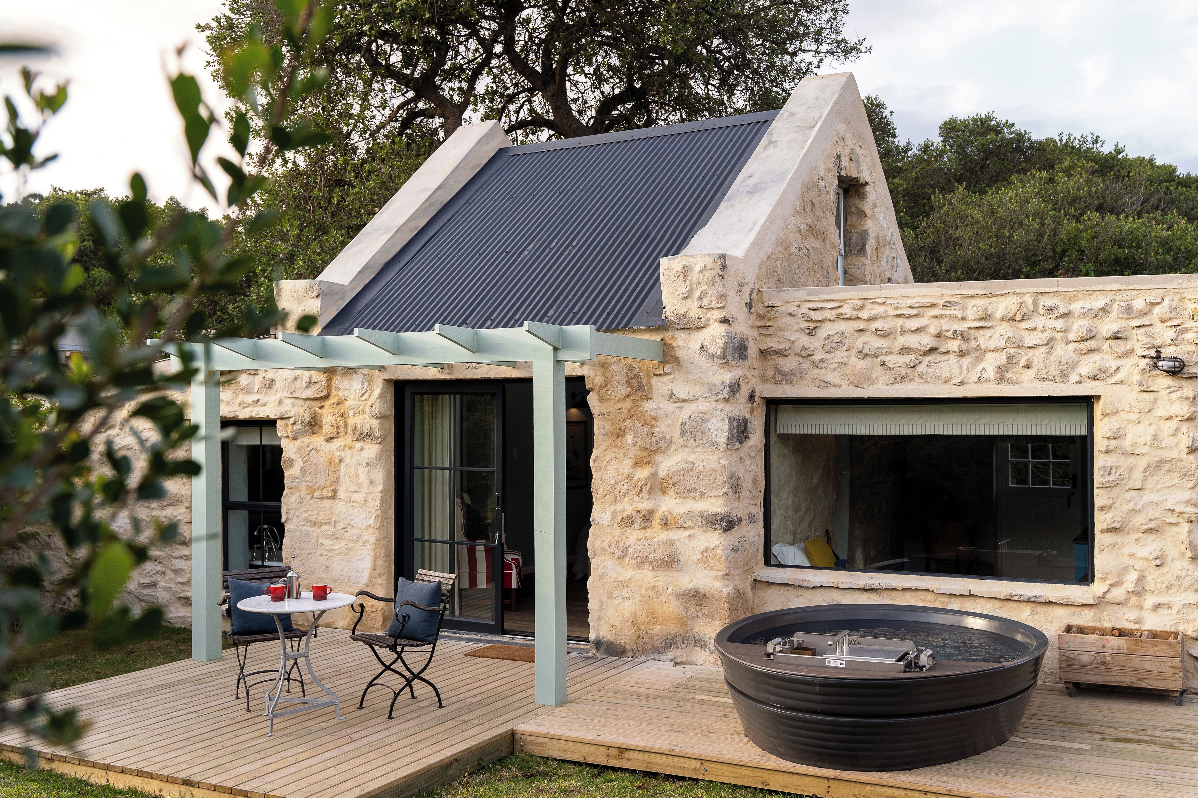 Une maison en pierre dotée d’une grande terrasse, d’un jacuzzi et d’une pergola.