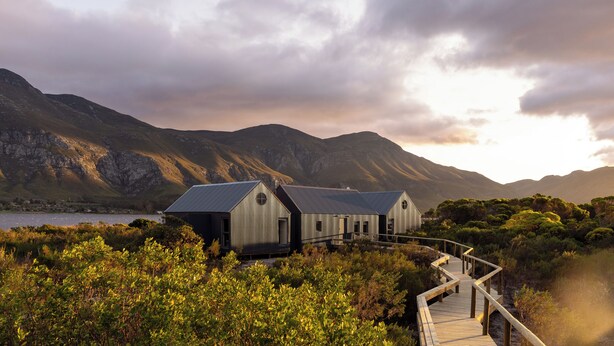 A rustic cabin with a wooden deck and a view of mountains and a lake. - Coot Club (Stanford)